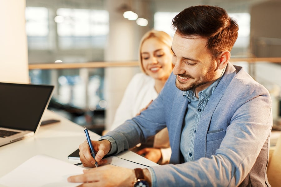 A man and women smiling and girl is receiving key from salesperson.